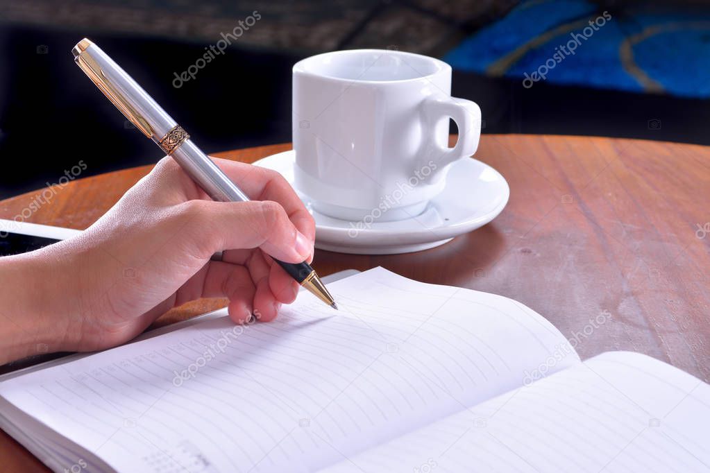 Business women hands working writing notebook on wooden desk, lighting effect