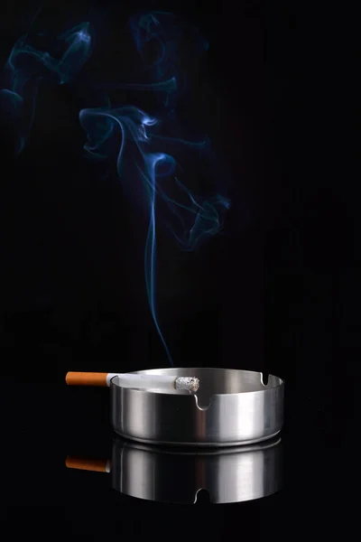 烟从烟灰缸中的香烟升起 — 图库照片
