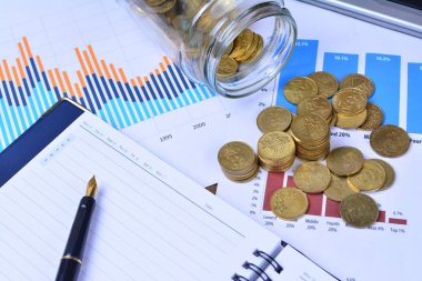 sikkeler, kavanoz, defter, çizelgeler ve masadaki kalem