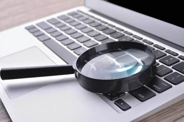 Laptop computer with magnifying glass, concept of search