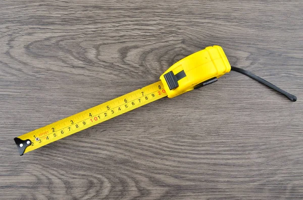 yellow tape measure on wood background