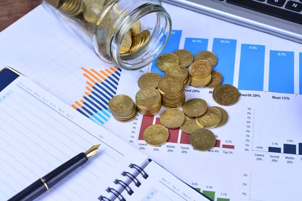 coins, jar, notebook, charts and pen on table