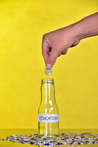 Mano poner moneda en botella con la palabra Educación - Concepto Financiero —  Fotos de Stock