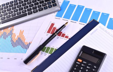 Boş defter ile hesap makinesi, klavye ve grafikler, çizelgeler ve iş tablo üzerinde dolma kalem. İş yerinde iş adamları