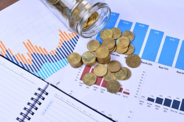 sikkeler, kavanoz, defter, çizelgeler ve masadaki kalem