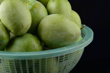 Siyah arka plan üzerinde sepet içinde taze yeşil mango