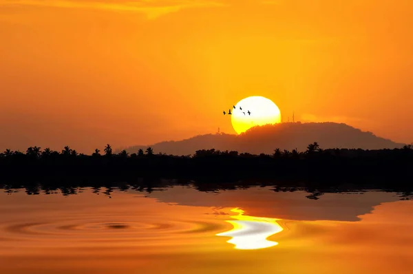 Pôr-do-sol dourado com metade do sol atrás da colina Fotografia De Stock