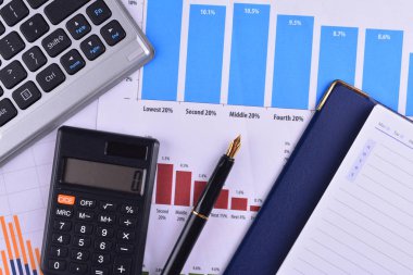 Boş defter ile hesap makinesi, klavye ve grafikler, çizelgeler ve iş tablo üzerinde dolma kalem. İş yerinde iş adamları