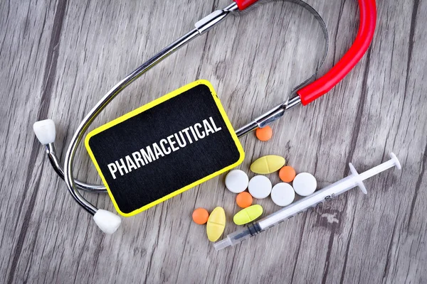 Pillen, spuit en stethoscoop met tekst farmaceutische — Stockfoto