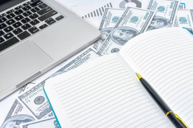 İş kavramı. Dizüstü bilgisayar, grafik ve banknot dolarları defter ve kalemle