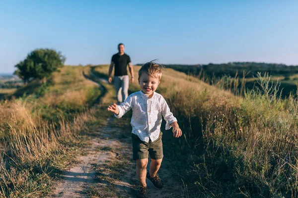 Adorable Feliz Niñito Corriendo Rural Camino Mientras Padre Caminar Detrás Imagen De Stock