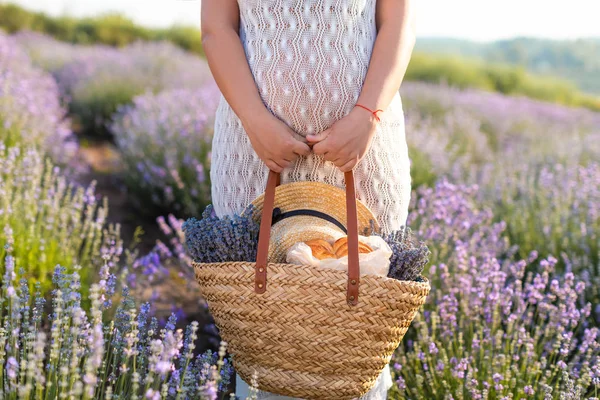 Image recadrée de femme enceinte en robe blanche tenant panier pique-nique au champ de lavande violette — Photo de stock