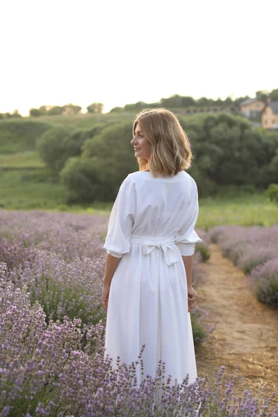 Rückseite der attraktiven Frau im weißen Kleid, die im violetten Lavendelfeld steht — Stockfoto