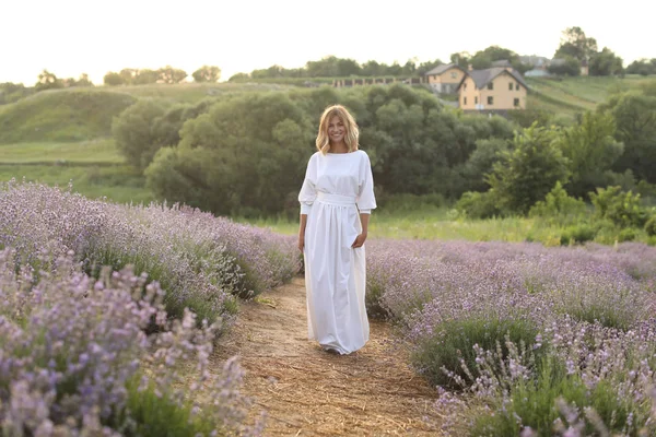 Mulher atraente em vestido branco em pé no caminho no campo de lavanda violeta — Fotografia de Stock