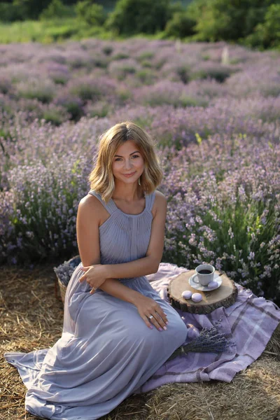 Atractiva mujer sentada en la manta en el picnic en el campo de lavanda violeta - foto de stock