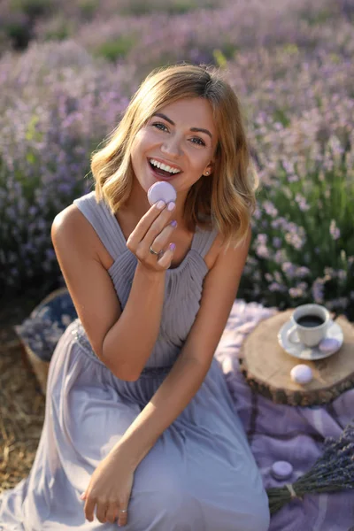Lachende attraktive Frau isst Macaron im violetten Lavendelfeld — Stockfoto