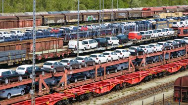 lots of new cars loaded on railway autorack wagons ready for shi clipart
