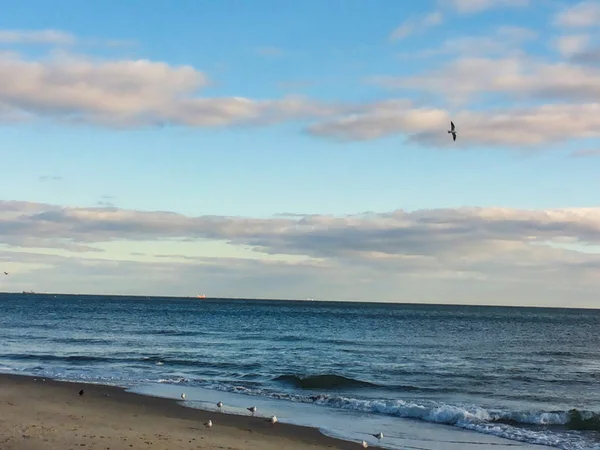 Denizin mavi genişliği ve plajdan bulutlar ile mavi gökyüzü görünümü. Açık ufuk. Tasarım ve doku arka planı için harika. 
