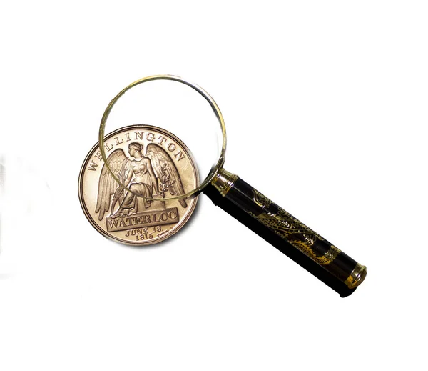 Arka planda izole edilmiş bir büyüteç altındaki eski bozuk para..  