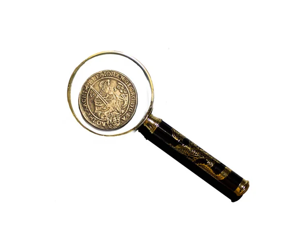 Arka planda izole edilmiş bir büyüteç altındaki eski bozuk para..  