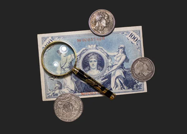 Arka planda izole edilmiş, eski para banknotları ve büyüteçle paralar 