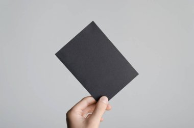 Siyah A6 Flyer / Kartpostal / Davetiye Model-up - Gri arkaplanda siyah bir el ilanı tutan erkek eller.