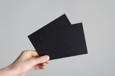 Siyah A6 el ilanı / kart / davet Mock-Up - erkek eller gri bir arka plan üzerinde siyah flyers holding.