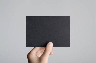 Siyah A6 Flyer / Kartpostal / Davetiye Model-up - Gri arkaplanda siyah bir el ilanı tutan erkek eller.