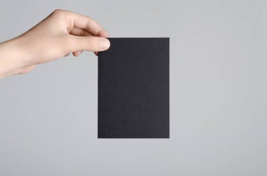 Siyah A6 Flyer / Kartpostal / Davetiye Model-up - Gri arkaplanda siyah bir el ilanı tutan erkek eller.