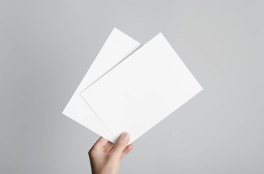 A5 el ilanı / davet Mock-Up - boş el ilanları gri bir arka plan üzerinde tutan eller erkek.