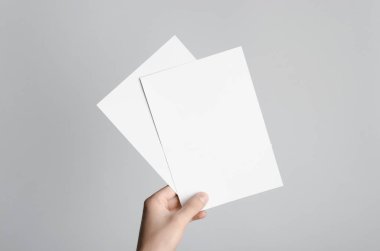 A5 el ilanı / davet Mock-Up - boş el ilanları gri bir arka plan üzerinde tutan eller erkek.