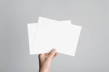 A5 el ilanı / davet Mock-Up - boş el ilanları gri bir arka plan üzerinde tutan eller erkek.