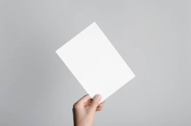 A5 el ilanı / davet Mock-Up - erkek eller gri bir arka plan üzerinde boş bir el ilanı holding.