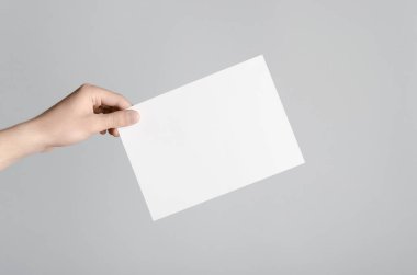 A5 el ilanı / davet Mock-Up - erkek eller gri bir arka plan üzerinde boş bir el ilanı holding.