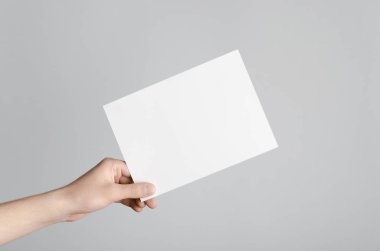 A5 el ilanı / davet Mock-Up - erkek eller gri bir arka plan üzerinde boş bir el ilanı holding.