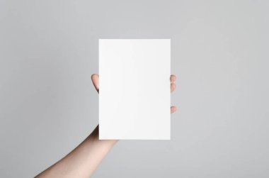 A5 el ilanı / davet Mock-Up - erkek eller gri bir arka plan üzerinde boş bir el ilanı holding.