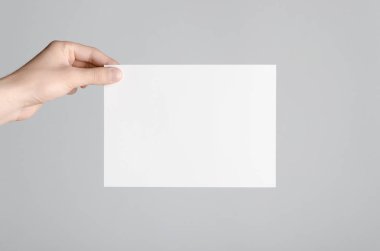A5 el ilanı / davet Mock-Up - erkek eller gri bir arka plan üzerinde boş bir el ilanı holding.