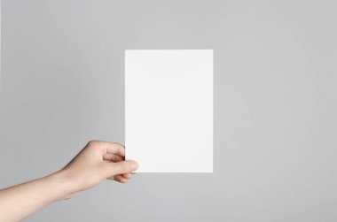 A5 el ilanı / davet Mock-Up - erkek eller gri bir arka plan üzerinde boş bir el ilanı holding.