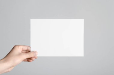 A5 el ilanı / davet Mock-Up - erkek eller gri bir arka plan üzerinde boş bir el ilanı holding.