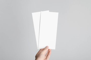 DL el ilanı Mock-Up-erkek elleri boş el ilanları gri bir arka plan üzerinde tutan.