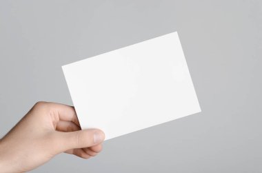 A6 el ilanı / kart / davet Mock-Up - erkek eller gri bir arka plan üzerinde boş bir el ilanı holding.