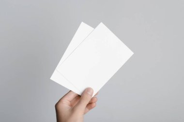 A6 el ilanı / kart / davet Mock-Up - boş el ilanları gri bir arka plan üzerinde tutan eller erkek.