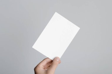 A6 el ilanı / kart / davet Mock-Up - erkek eller gri bir arka plan üzerinde boş bir el ilanı holding.