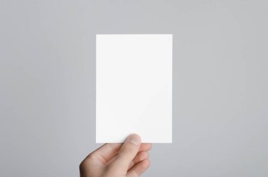 A6 el ilanı / kart / davet Mock-Up - erkek eller gri bir arka plan üzerinde boş bir el ilanı holding.