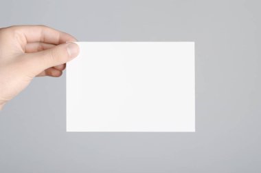 A6 el ilanı / kart / davet Mock-Up - erkek eller gri bir arka plan üzerinde boş bir el ilanı holding.