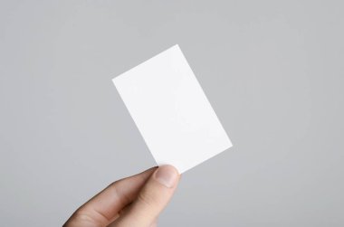 Kartvizit Mock-Up (85x55mm) - erkek gri bir arka plan üzerinde boş bir kart tutan eller.