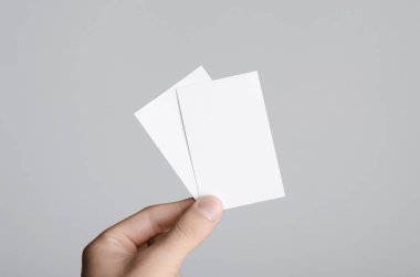 Kartvizit Mock-Up (85x55mm) - erkek gri bir arka plan üzerinde boş kart tutan eller.