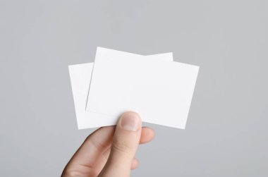 Kartvizit Mock-Up (85x55mm) - erkek gri bir arka plan üzerinde boş kart tutan eller.