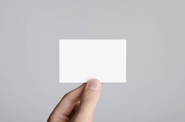 Kartvizit Mock-Up (85x55mm) - erkek gri bir arka plan üzerinde boş bir kart tutan eller.