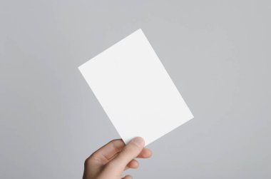 A6 el ilanı / kart / davet Mock-Up - erkek eller gri bir arka plan üzerinde boş bir el ilanı holding.